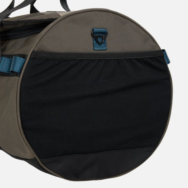 Rugged duffle bag in earthy tones with black straps, blue accent detailing, and a durable design. Features multiple compartments, reinforced handles, and an adjustable shoulder strap for versatile carrying.