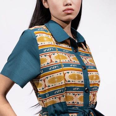 A close up of a woman in a button up yellow and teal dress thats star wars jedi inspired with a striped tapestry pattern 