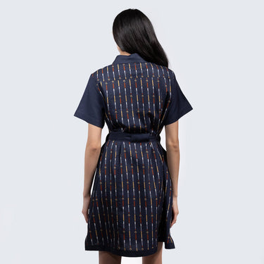 A woman standing backwards in a button up navy dress thats star wars rebel inspired with a striped pattern 