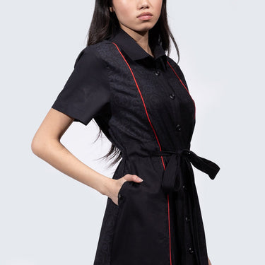 Woman in a button up black dress thats star wars imperial inspired with a geometric pattern and red details