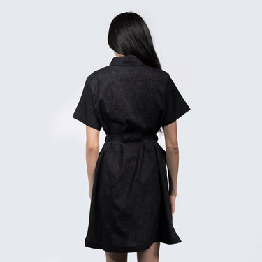 A woman standing backwards in a black dress thats star wars imperial inspired with a geometric pattern 