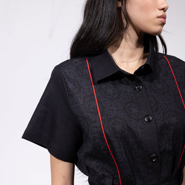 Close up of a woman in a button up black dress thats star wars imperial inspired with a geometric pattern and red details
