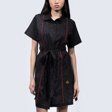 Women in a button up black dress thats star wars imperial inspired with a geometric pattern and red details