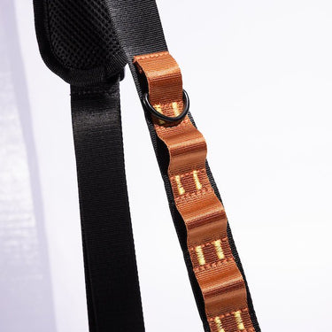 The photo shows a close up detailing of the shoulder strap. Featured is the orange decorative detailing. The detailing has loops for attaching clips and a tech case. The top loop has a "D"-Ring attached.
