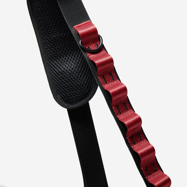 The photo shows a close up detailing of the shoulder strap. Featured is the Red decorative detailing. The detailing has loops for attaching clips and a tech case. The top loop has a "D"-Ring attached.