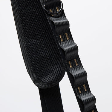 The photo shows a close up detailing of the shoulder strap. Featured is the black decorative detailing. The detailing has loops for attaching clips and a tech case. The top loop has a "D"-Ring attached.