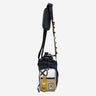 The photo shows a crossbody bag designed for carrying a water bottle. The bag features a drawstring closure at the top, a front zippered pocket, and a Molle Loop Strap. The adjustable black strap has a padded section for comfort and gold molle cord with holes to attach clips and a tech organizer bag (Not pictured). The bag is Navy with Beige, White and Gold Accents.
