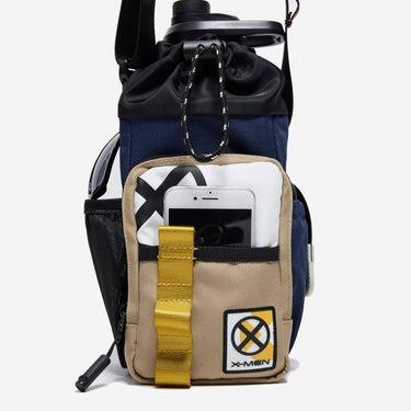 The photo shows a close up of the bags main outer zipper pouch. The pouch has an xmen patch on the bottom right and an xmen logo printed on the top left. There is a pocket on this pouch showing an iphone being held. 