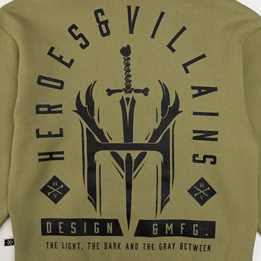 The photo is a close up of the print on the back of a green hoodie. The print is in a tombstone shape and features a large logo of an "H" and "V" with a dagger going through. The words "Heroes & Villians" arch over the design in an arch shape. 