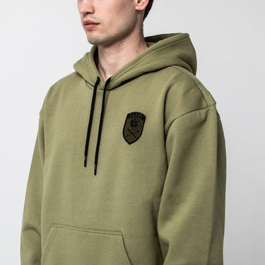 The photo is a close up of a man in a green hoodie to show the detail of a patch on the right chest area. The patch is military style with the word "Cadet" at the top and a Skull and cross bones underneath. The Skull is wearing a hat!