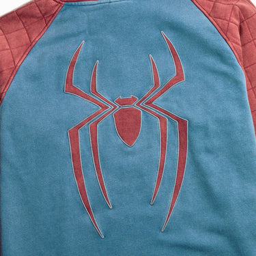 Man in a Spider-Man themed pullover hoodie with a blue body, quilted dusty red sleeves and hood, and a red spider logo on the back, shown against a light gray background.