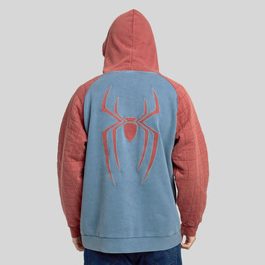 Man in a Spider-Man themed pullover hoodie with a blue body, quilted dusty red sleeves and hood, and a silver spider logo on the chest, shown against a light gray background.