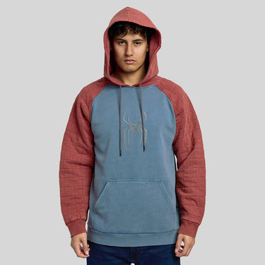 Man in a Spider-Man themed pullover hoodie with a blue body, quilted dusty red sleeves and hood, and a silver spider logo on the chest, shown against a light gray background.