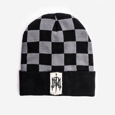 A beanie featuring a black and gray checkered pattern across the top. The folded cuff is solid black with a rectangular white patch in the center, displaying an ornate embroidered monogram logo in black. The patch has slightly frayed edges for a rugged, vintage look.