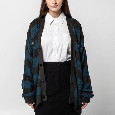 Woman standing wearing the Critical Role The Mighty Nein Brown and blue striped Cardigan over a white button up blouse and a black skirt