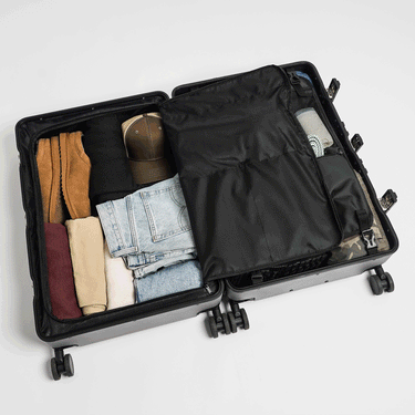 Gif showing a packed suitcase. Thegif flips between a photo of the zipper compartment closed and toiletry hanger attached to a photo of the toiletry hanger removed and the zippered compartment open