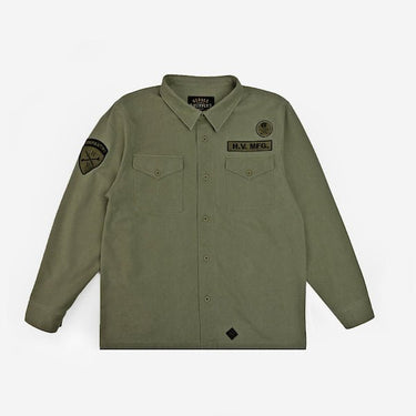 The photo shows a military style shirt jacket. The jacket is a thick canvas material and features 2 patches on the right chest and a patch on the left sleeve. The jacket has buttons as a closer and 2 chest pockets. 