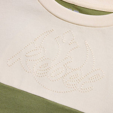 a close up of the top cream panel showing a single stitch embroidery that says "Rebel" with the rebel emblem behind the word. 