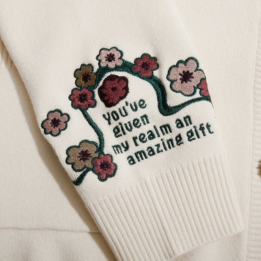 Close up of embroidery on a white cardigan that reads "Youve given my realm an amazing gift"