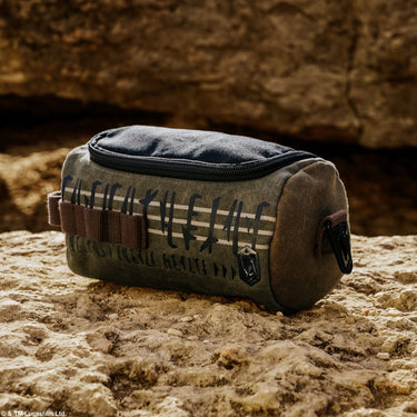 Star Wars The Mandalorian Canvas toiletry bag with text and brown strap on a a rocky surface