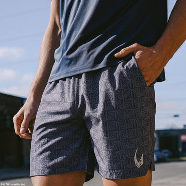 Person wearing patterned star wars athletic shorts with a mudhorn logo, standing outdoors.