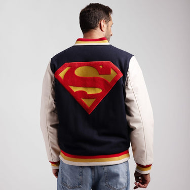 Man wearing a Superman-themed varsity jacket on a plain background