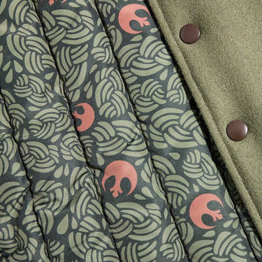 The photo shows up close detailing of the varsity jackets inner lining. The lining is dark green with a lighter green braided pattern and small Rebel logos scattered throughout. 