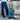 Blue suitcase with X-Men logo on a concrete gray background