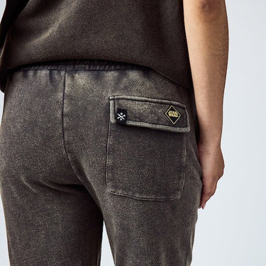 close-up of a person wearing black sweatpants with a back pocket featuring two small patches—one with the Star Wars logo in a yellow diamond shape 