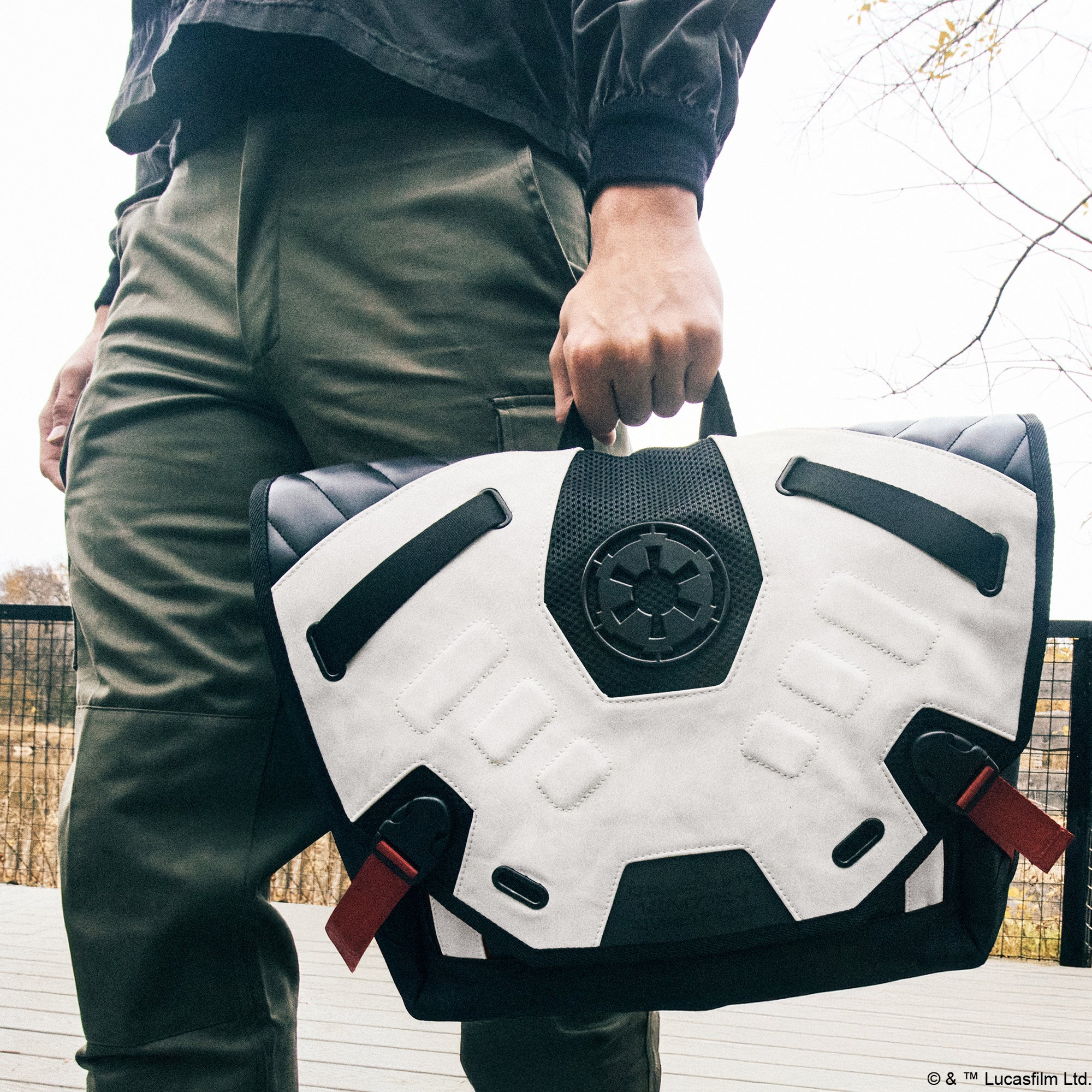 Man carrying Heroes & Villains Star Wars Imperial Army Bike Messenger Bag with a white and black design, featuring the Galactic Empire emblem, red strap accents, and a sleek, modern finish.