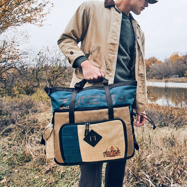 Male carrying the Heroes & Villains Rebel Teal Commuter Bag in nature.