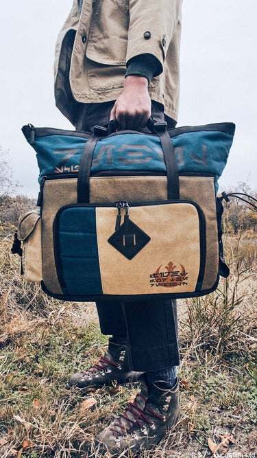 Close-up of a man carrying the Heroes & Villains Rebel Teal Commuter Bag in a nature scene.