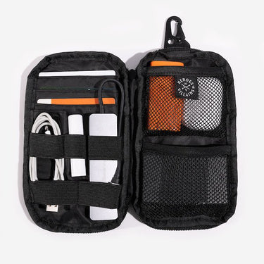 The same pouch is opened, revealing multiple compartments and elastic straps for organizing small items. Inside, there are mesh pockets and elastic loops holding various essentials, including charging cables, a power bank, pens, and a small orange case. A "Heroes & Villains" label is visible on the inner pocket.