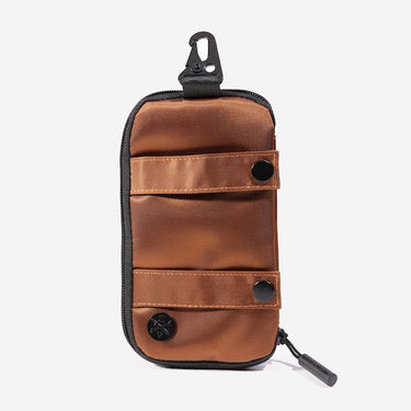 A compact, orange and black zippered pouch with a hook clip at the top. The pouch features a metal decal at the bottom with the "Heroes and Villains" logo. The pouch has 2 strap horizontal across it with black button closures. 