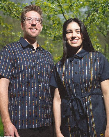 Couples standing in a park wearing a star wars themed rebel button up shirt and matching button up dress
