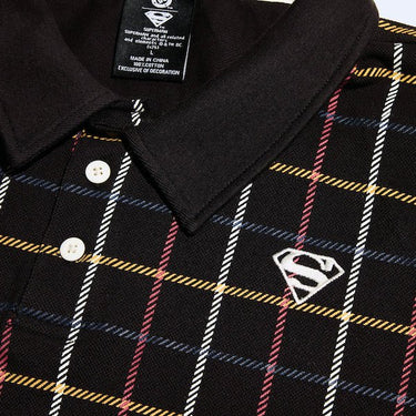 A close up of a black plaid polo style shirt with red, white, blue and yellow stripe pattern. The photo shows a focused on the 2 button details and the "S-Shield" Embroidered on the chest