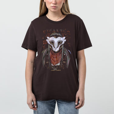 A female model wearing a brown Arcane x League of Legends t-shirt featuring Ekko wearing his signature mask and red scarf. The design includes stylized graffiti-like text, with ‘Ekko’ at the top and ‘Arcane’ and ‘League of Legends’ at the bottom in a bold font. The artwork has a gritty, cyberpunk aesthetic with metallic and distressed details."