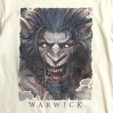 A cream-colored League of Legends t-shirt featuring a detailed illustration of Warwick. The design showcases his snarling, beastly face with glowing orange eyes, sharp fangs, and dark fur. The artwork has a distressed, grunge-style border, giving it a raw and intense look. 'Warwick' is printed in bold, stylized lettering below the image