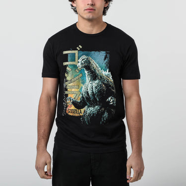 Male modeling Black colored T-shirt featuring a vintage-style graphic of Godzilla roaring with a distressed design, Japanese text, and green block lettering.