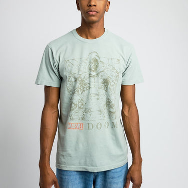 Person wearing a light green t-shirt with Marvel graphic design on a plain background