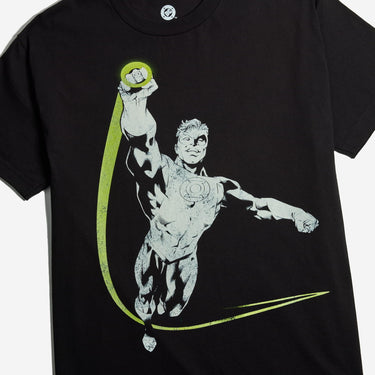 A black short-sleeve graphic t-shirt featuring a stylized print of Green Lantern flying upwards with a bright yellow-green cape and circular emblem on the chest, set against a light gray background.