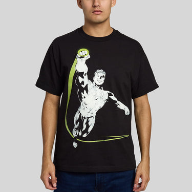 A man wearing A black short-sleeve graphic t-shirt featuring a stylized print of Green Lantern flying upwards with a bright yellow-green cape and circular emblem on the chest, set against a light gray background.