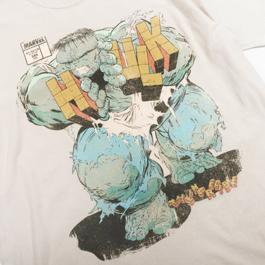 Off White T-shirt with a graphic design of a The Incredible Hulk Comic Cover depicting The Hulk pushing through his name between the "H" and "ULK" on a beige background