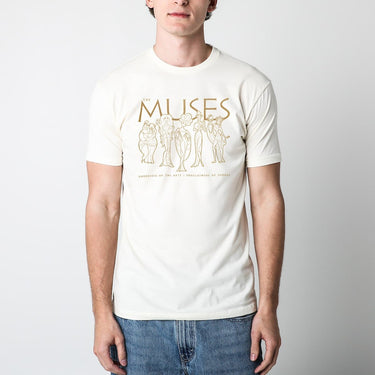 Man in a cream T-shirt with graphic drawings of five characters and text reading "THE MUSES."