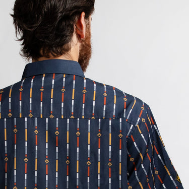 A close up of a man standing backwards in a button up navy shirt with a star wars rebel motif in a striped pattern