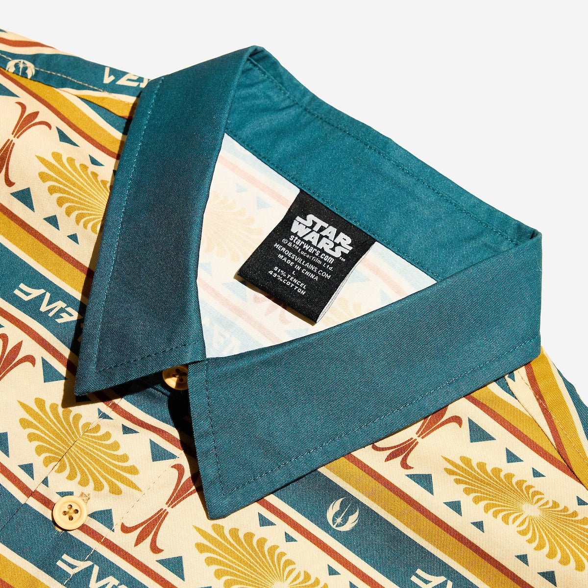 A close up of a button up yellow and teal shirt with a star wars jedi motif in a striped pattern
