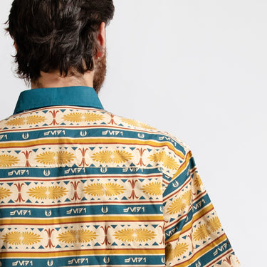 A close up of a man in a button up yellow and teal shirt with a star wars jedi motif in a striped pattern