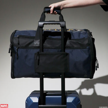 Navy duffel bag with Marvel X-Men logo held by a hand against a gray background