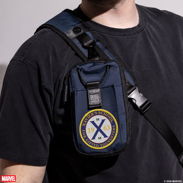 Person wearing a blue crossbody bag with Xavier's School emblem, on a plain background.